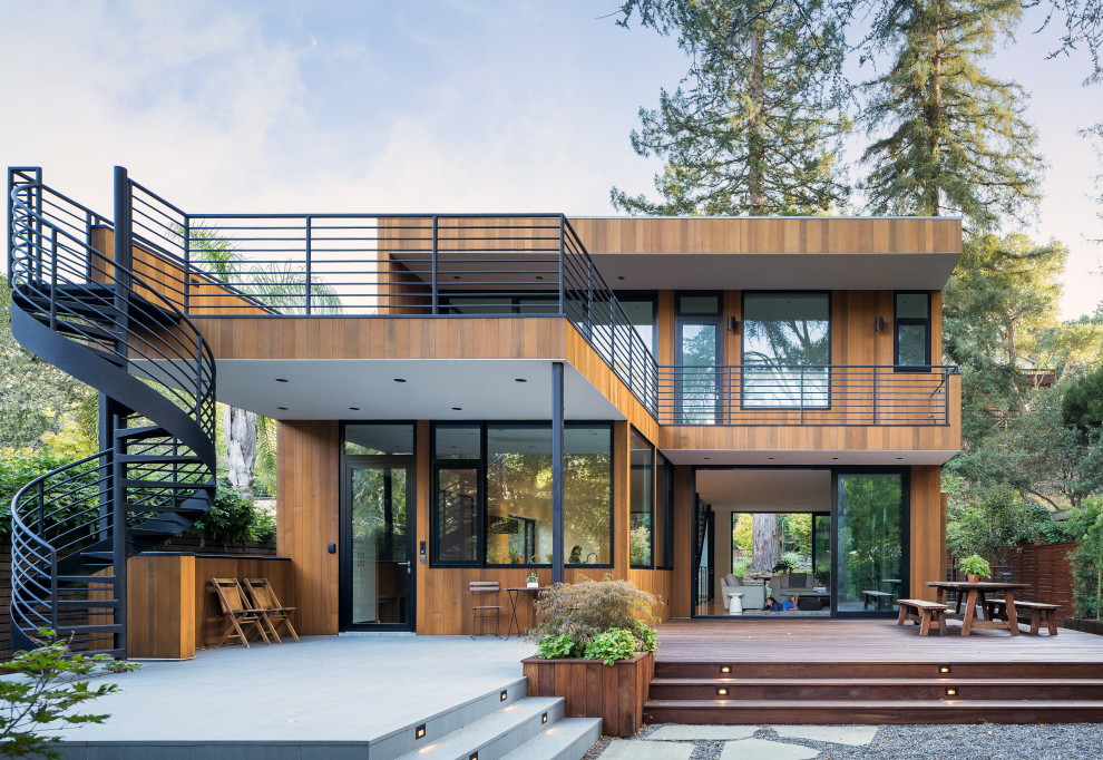 Inspiration för stora moderna bruna hus, med två våningar, platt tak och tak i mixade material