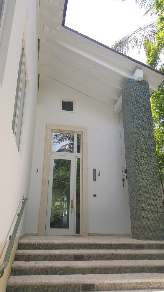This is an example of a large and white contemporary render house exterior in Miami with three floors and a pitched roof.