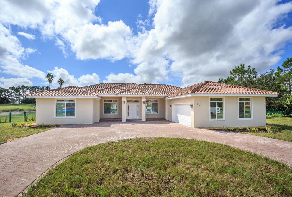 Photo of a medium sized and beige world-inspired bungalow render detached house in Orlando with a hip roof and a tiled roof.