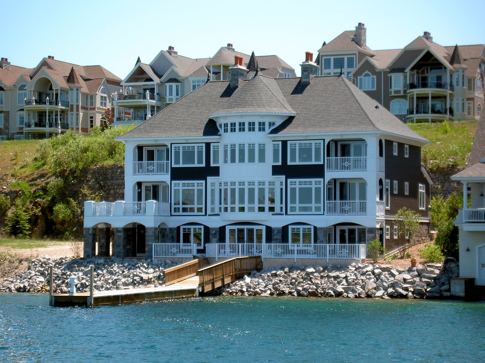 Cette image montre une grande façade de maison marron marine en bois à deux étages et plus.