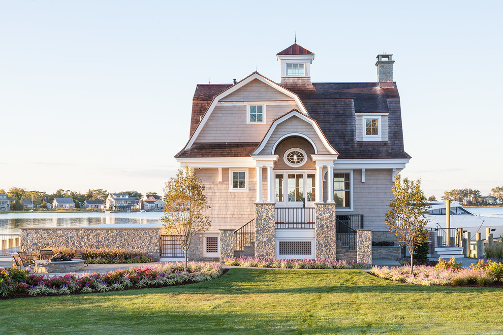 На фото: маленький, двухэтажный, деревянный, серый дом в морском стиле с мансардной крышей и крышей из смешанных материалов для на участке и в саду