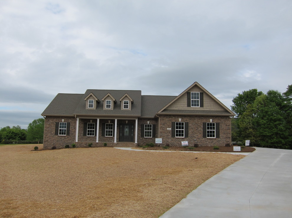 Cette image montre une façade de maison marron traditionnelle en brique de taille moyenne et de plain-pied avec un toit à deux pans et un toit en shingle.
