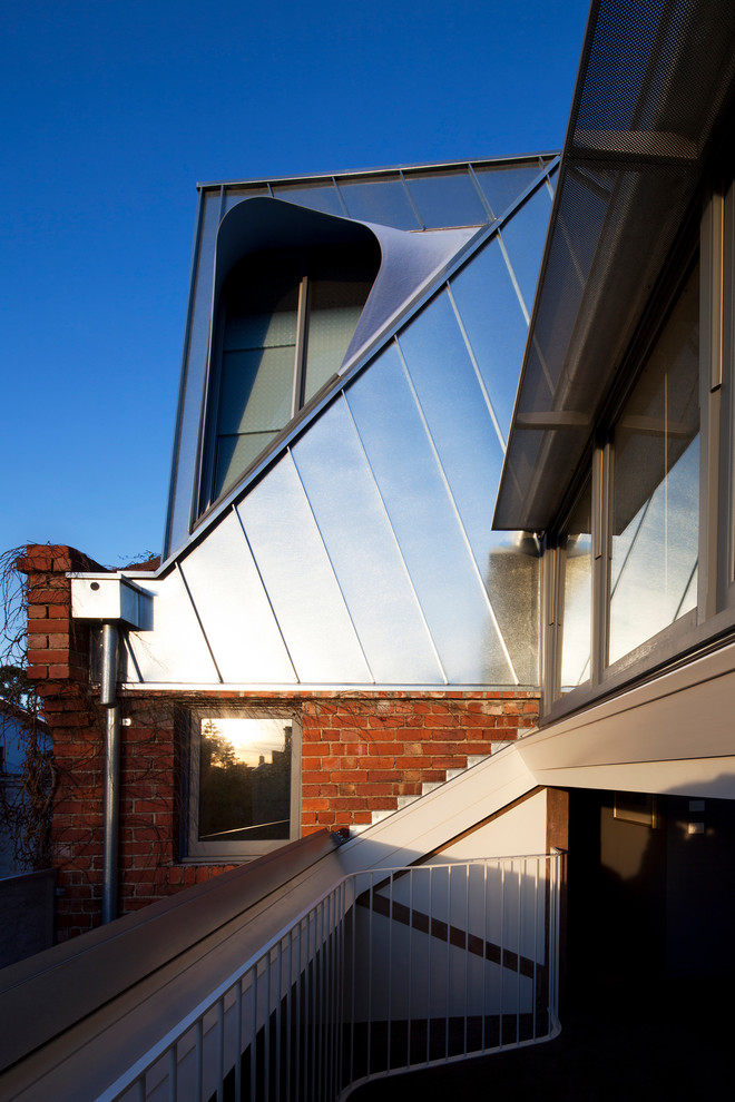 На фото: большой, двухэтажный дом в современном стиле с облицовкой из металла и двускатной крышей