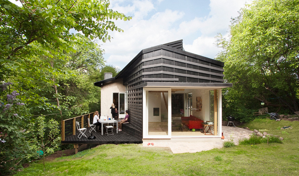 Photo of a medium sized and black scandi two floor house exterior in Copenhagen with wood cladding and a flat roof.