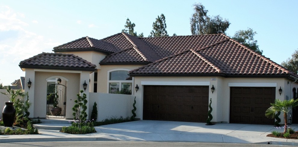 Mid-sized mediterranean beige one-story stucco gable roof idea in Other
