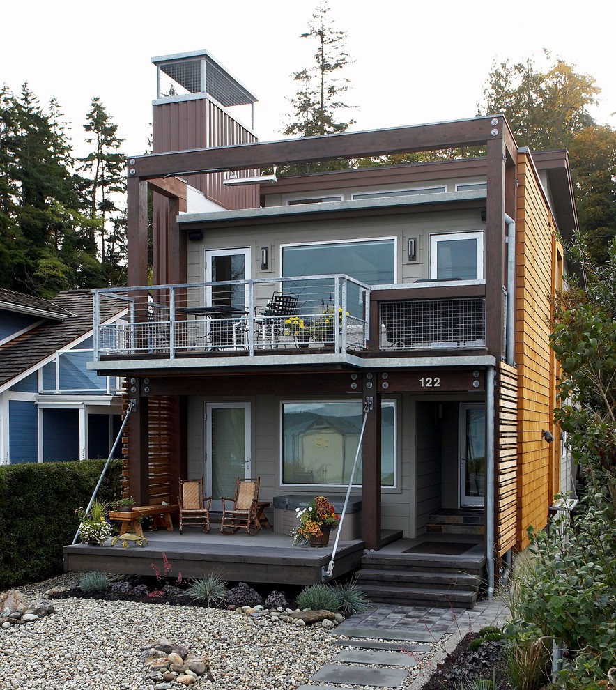 Modelo de fachada de casa multicolor actual de tamaño medio de dos plantas con revestimientos combinados, tejado de un solo tendido y tejado de metal