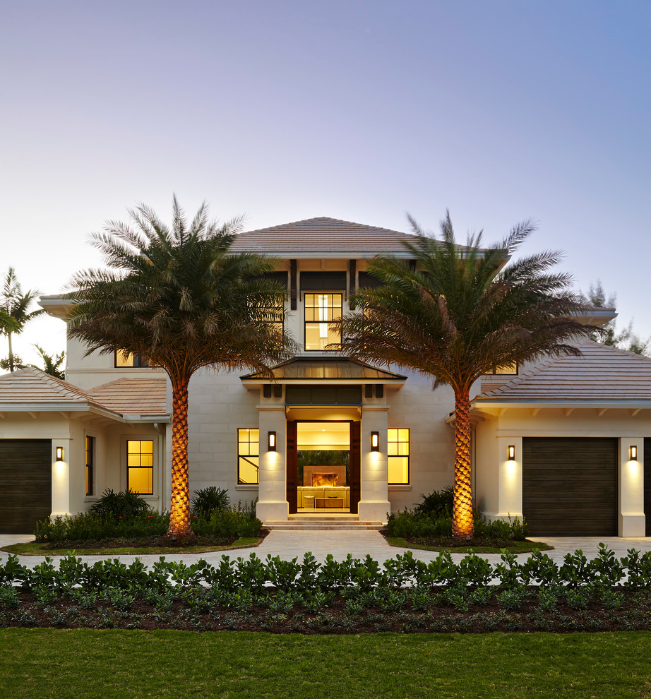 Inspiration for a large tropical white two-story stucco exterior home remodel in Miami with a hip roof