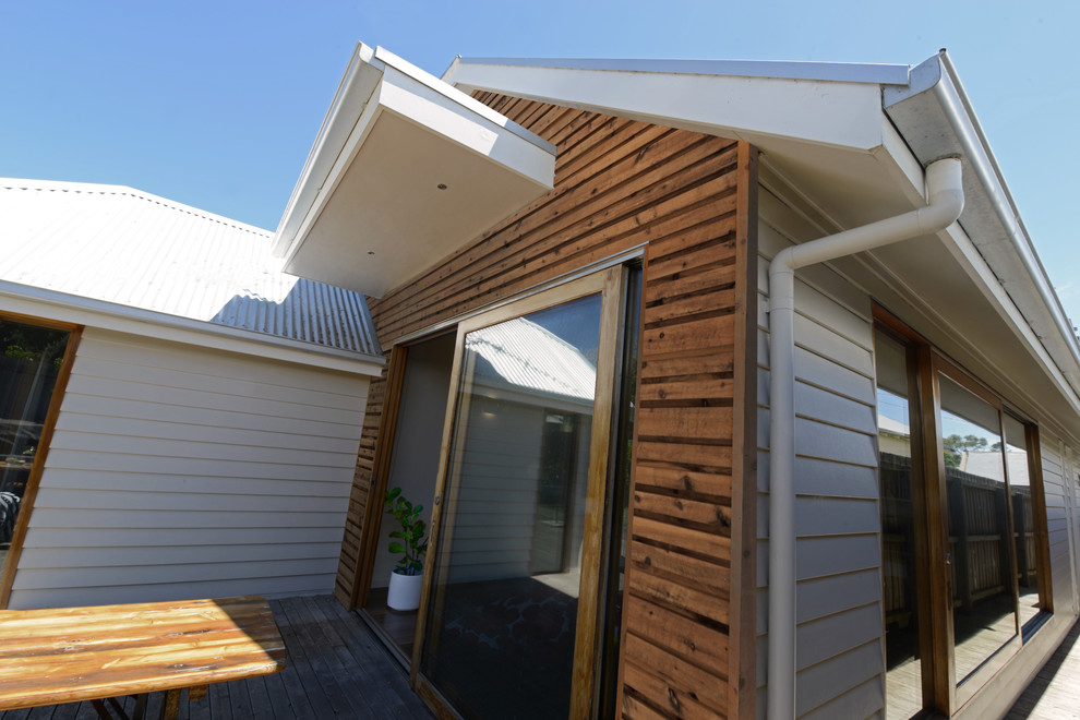 Idées déco pour une petite façade de maison blanche bord de mer en bois de plain-pied avec un toit à croupette et un toit en métal.
