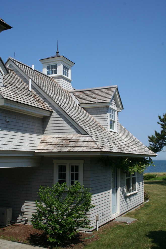 Ejemplo de fachada gris marinera de dos plantas con revestimiento de madera y tejado a dos aguas