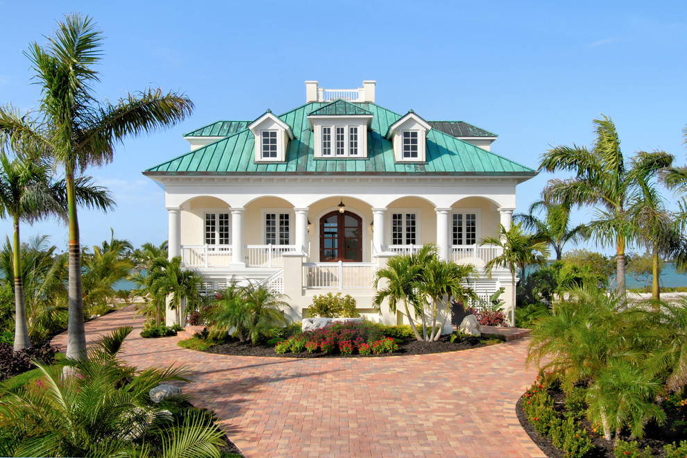 Diseño de fachada de casa beige tropical grande de dos plantas con revestimiento de estuco y tejado de metal