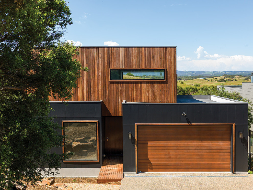 Inspiration pour une façade de maison marron design à un étage avec un revêtement mixte et un toit plat.