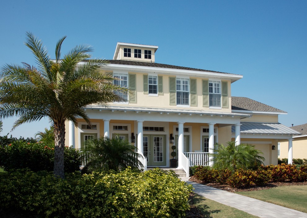 Example of a mid-sized island style yellow two-story stucco house exterior design in Tampa with a hip roof and a mixed material roof