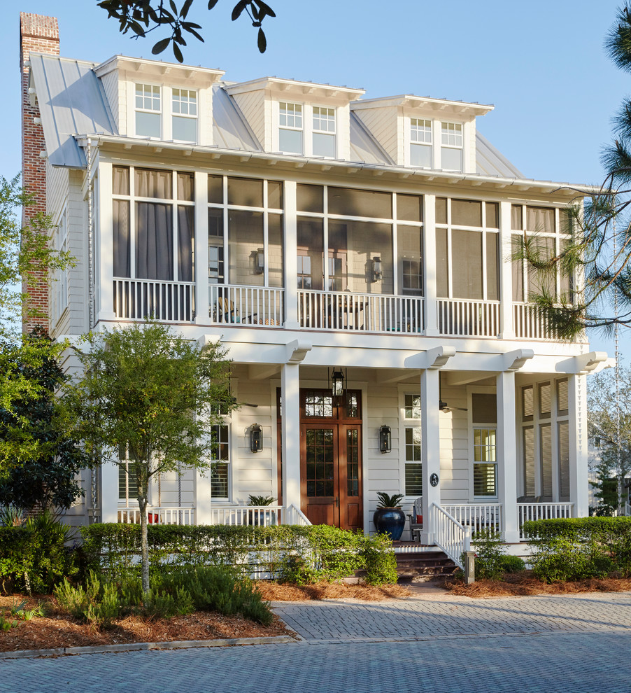 Example of a beach style white two-story exterior home design with a metal roof
