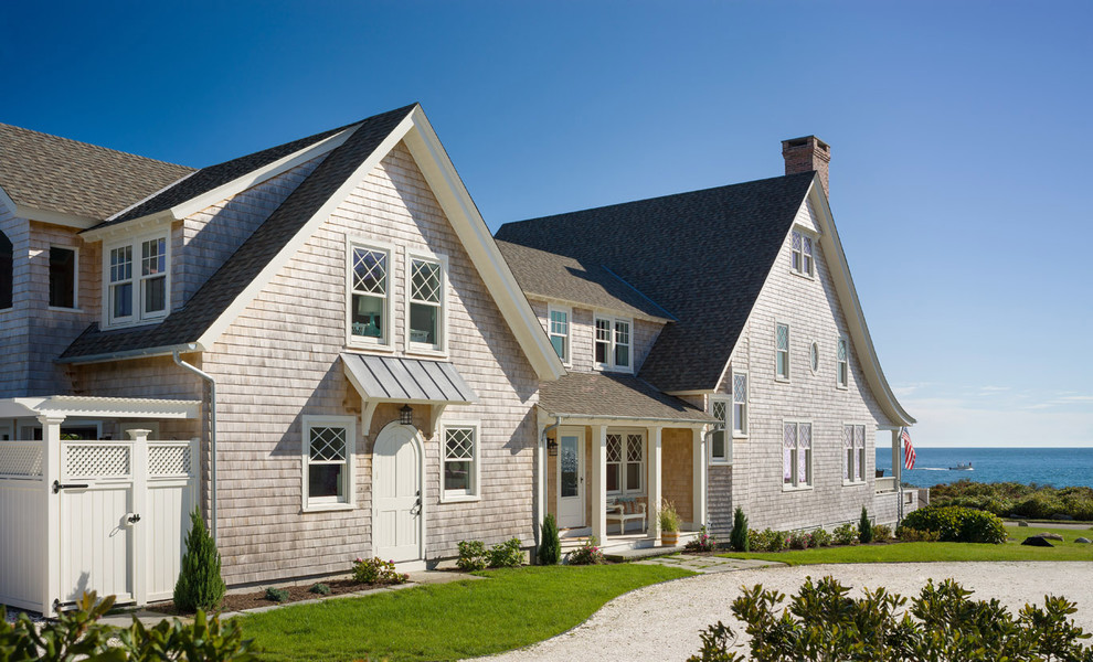 Diseño de fachada de casa beige costera con revestimiento de madera, tejado a dos aguas y tejado de teja de madera