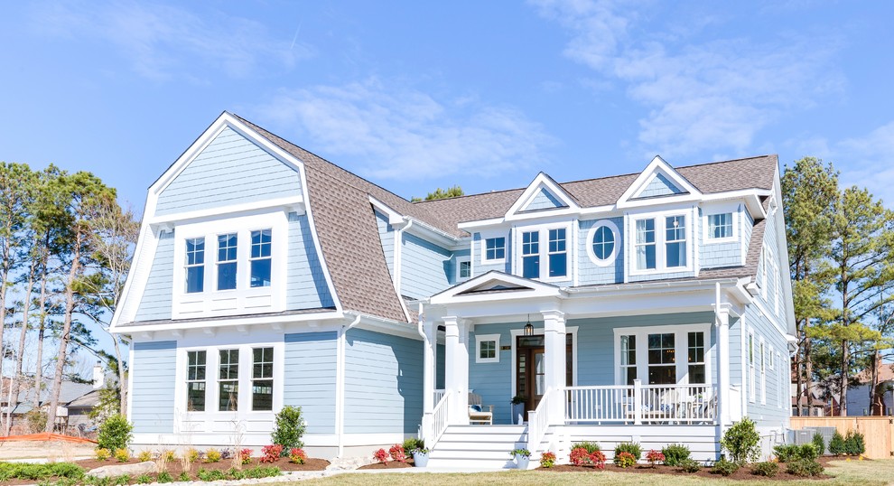 Imagen de fachada de casa azul costera grande de dos plantas con revestimiento de hormigón, tejado a doble faldón y tejado de teja de madera