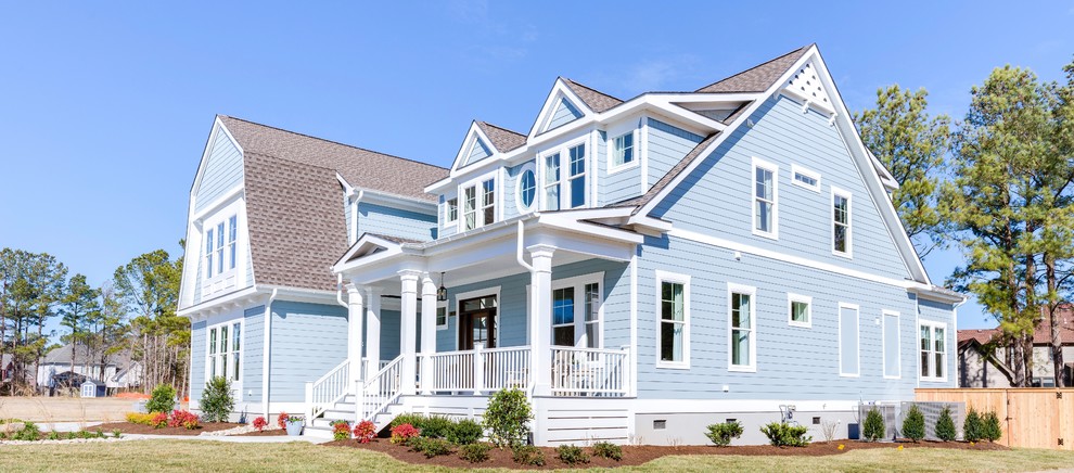 Diseño de fachada de casa azul marinera grande de dos plantas con revestimiento de hormigón, tejado a doble faldón y tejado de teja de madera