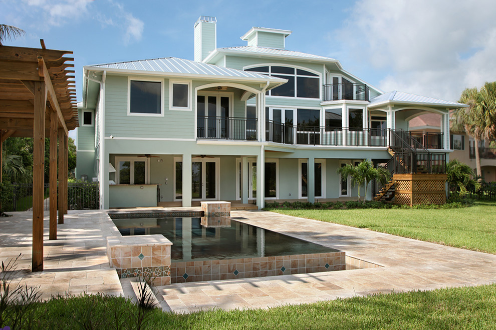 Large island style blue three-story wood exterior home photo in Miami with a hip roof
