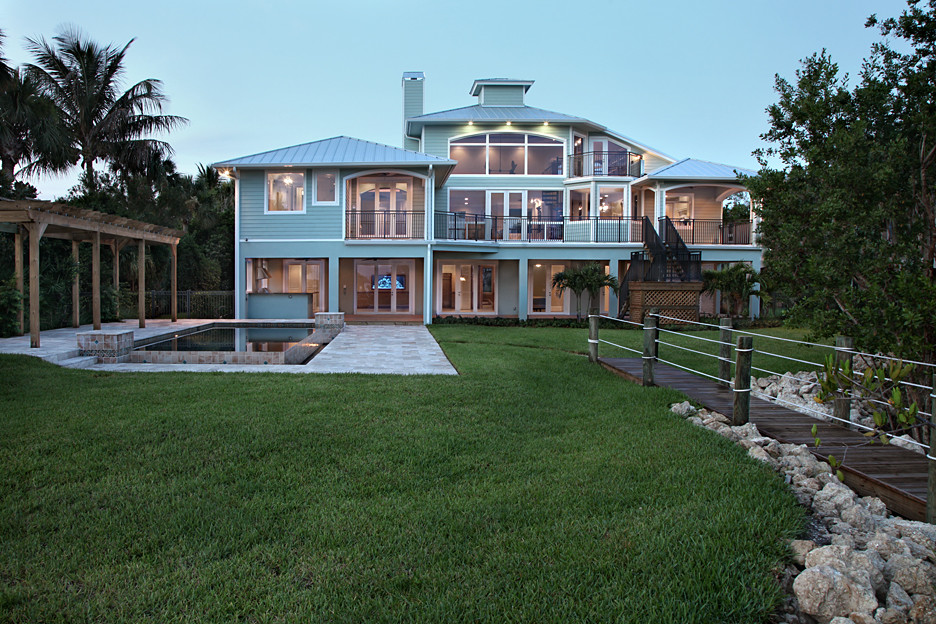 Inspiration for a large tropical blue three-story wood exterior home remodel in Miami with a hip roof