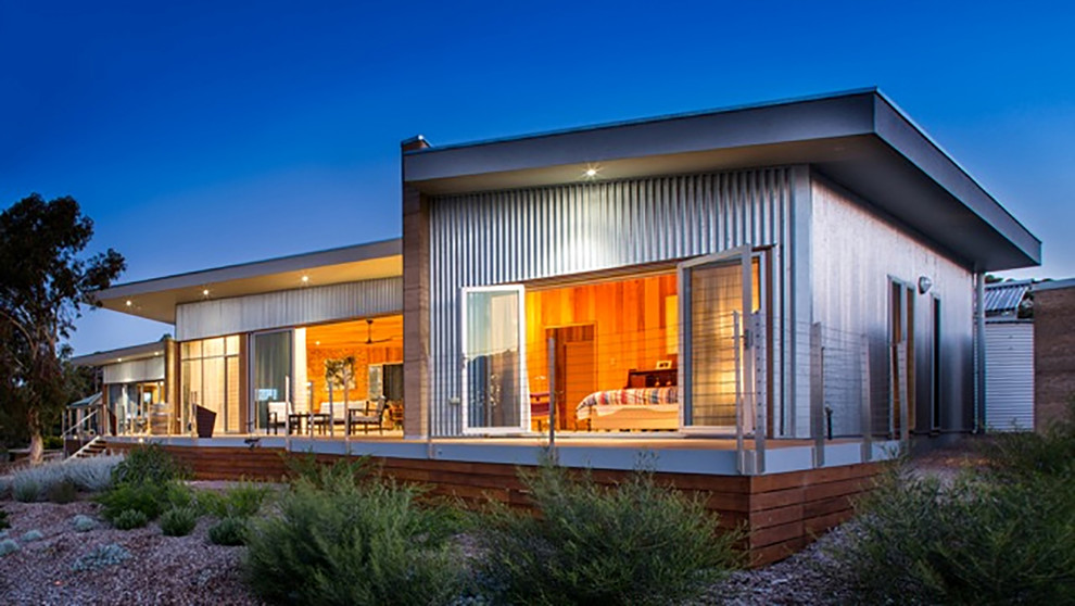 Свежая идея для дизайна: одноэтажный, серый дом в современном стиле с облицовкой из металла и плоской крышей - отличное фото интерьера