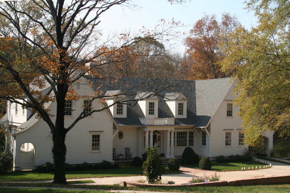Immagine della facciata di una casa grande bianca classica a due piani con rivestimento in legno e tetto a capanna