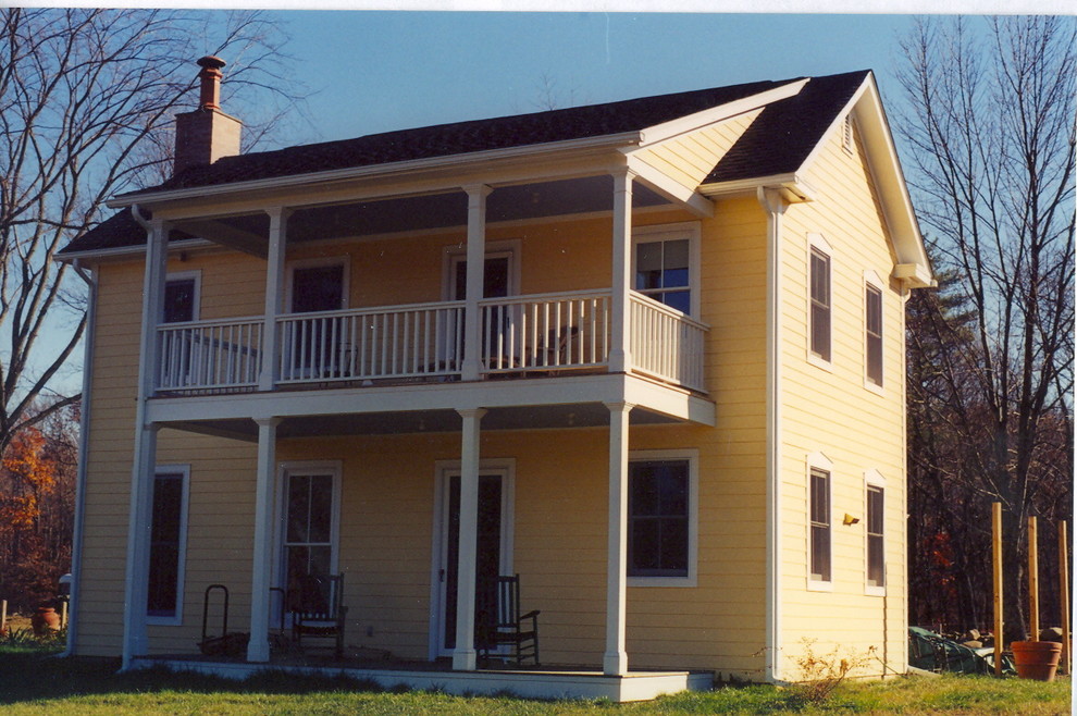 Imagen de fachada de casa amarilla campestre grande de dos plantas con revestimiento de madera, tejado a dos aguas y tejado de teja de madera