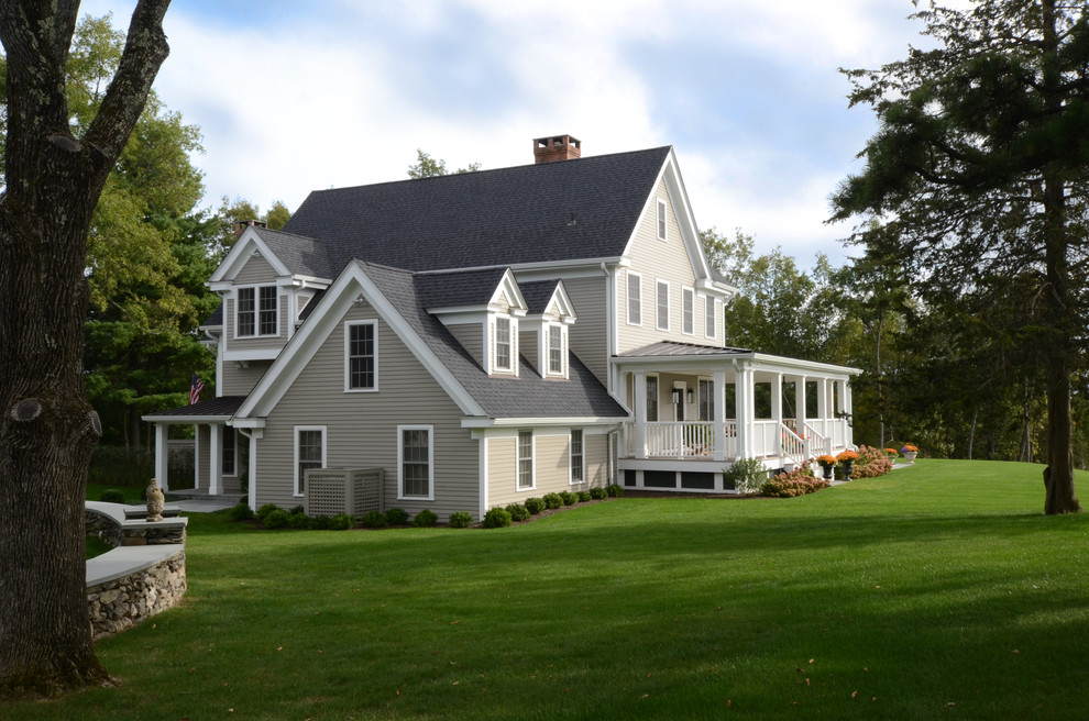 Modelo de fachada beige de estilo de casa de campo grande de dos plantas con revestimiento de madera y tejado a dos aguas