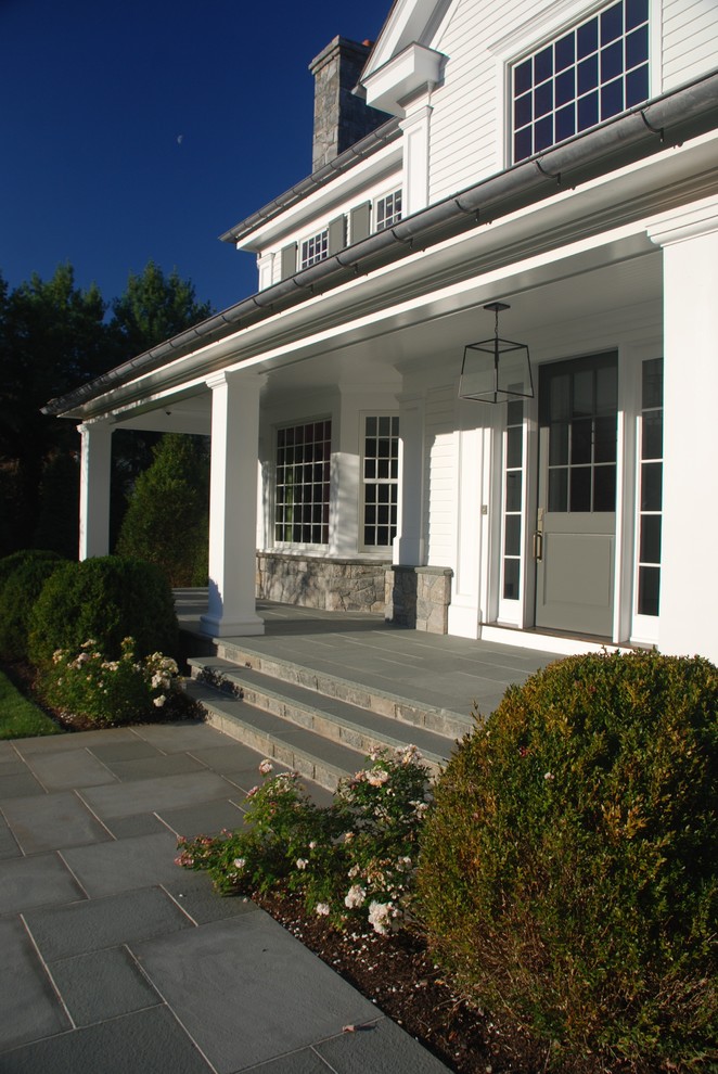 Cette image montre une grande façade de maison blanche à un étage avec un revêtement en vinyle et un toit à quatre pans.
