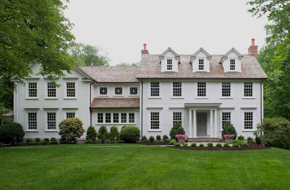 White classic house exterior in New York with three floors, vinyl cladding and a pitched roof.