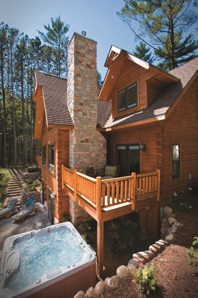 На фото: большой, деревянный, коричневый дом в стиле рустика с разными уровнями и двускатной крышей с