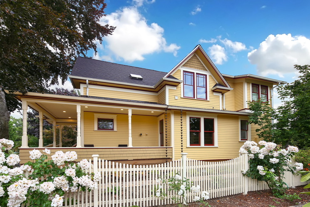 Diseño de fachada de casa amarilla clásica con revestimiento de aglomerado de cemento, tejado a dos aguas y tejado de teja de madera