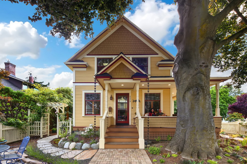 Klassisches Einfamilienhaus mit gelber Fassadenfarbe, Satteldach, Faserzement-Fassade und Schindeldach in Seattle