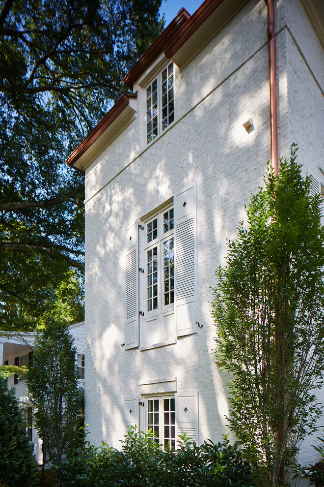 Bild på ett funkis vitt hus, med tre eller fler plan och tegel