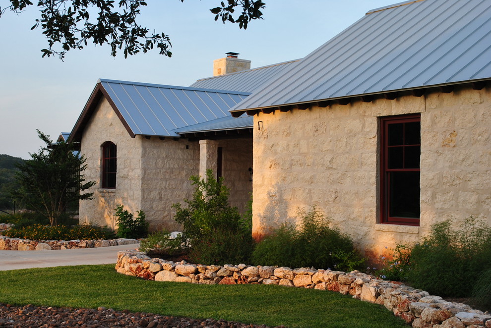 Imagen de fachada beige de estilo de casa de campo grande de una planta con revestimiento de piedra y tejado a dos aguas