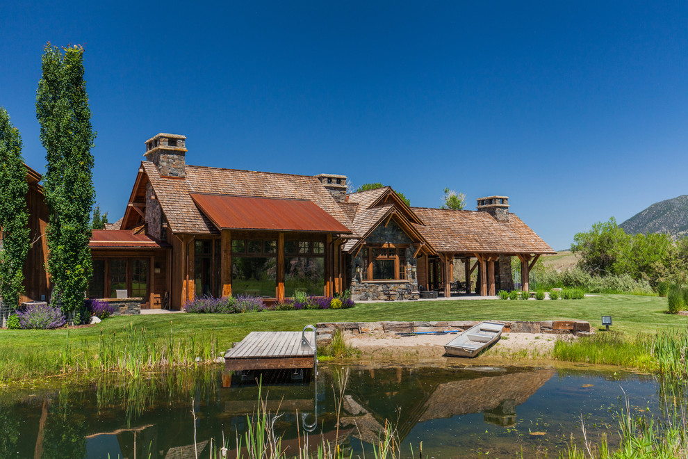 Пример оригинального дизайна: огромный, двухэтажный, деревянный, коричневый дом в стиле рустика с двускатной крышей