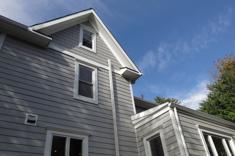 Réalisation d'une grande façade de maison grise minimaliste à un étage avec un revêtement en vinyle, un toit à deux pans et un toit en shingle.