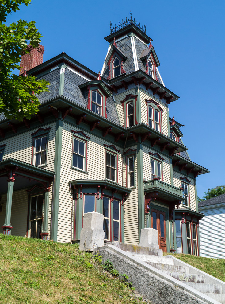 Photo of a large and multi-coloured victorian detached house in Boston with three floors, wood cladding and a shingle roof.