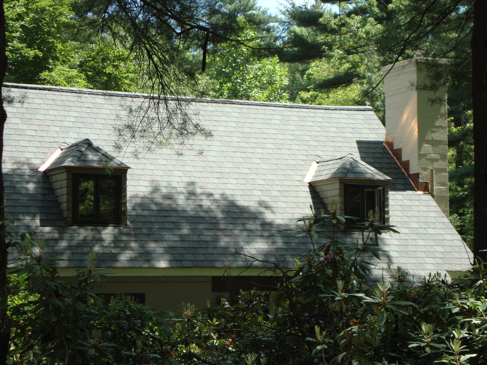 Foto della villa grande verde classica a due piani con rivestimento in mattoni e copertura a scandole