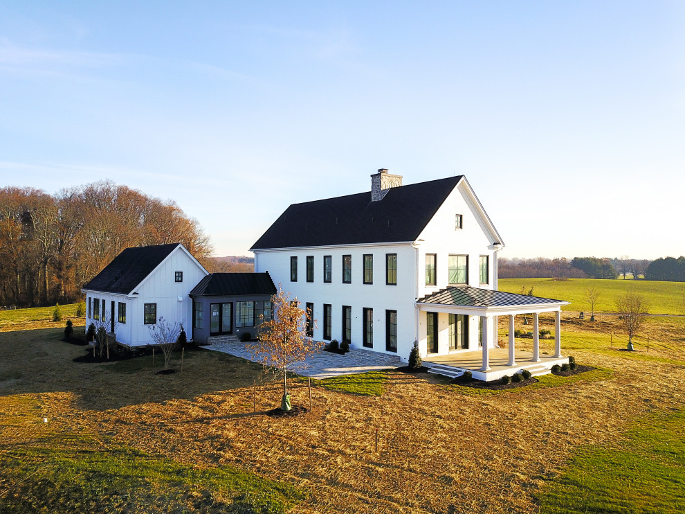 Aménagement d'une façade de maison blanche campagne en planches et couvre-joints à un étage avec un revêtement mixte, un toit mixte et un toit noir.