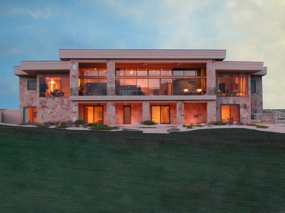 Example of a large trendy beige two-story stone flat roof design in Denver
