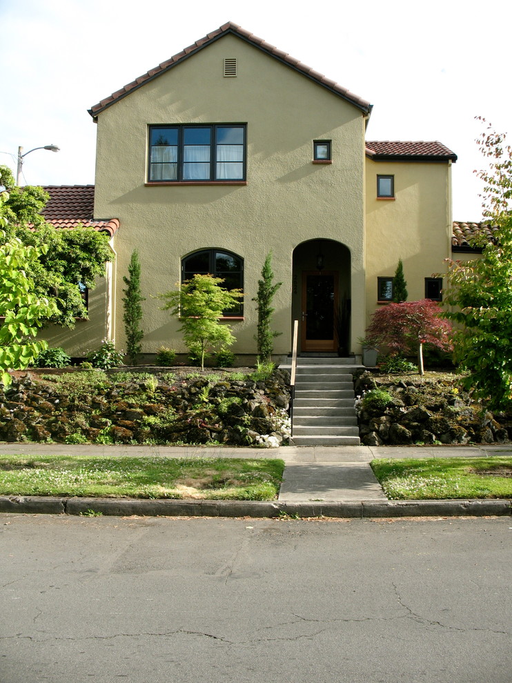 Esempio della facciata di una casa piccola gialla mediterranea a due piani con rivestimento in stucco
