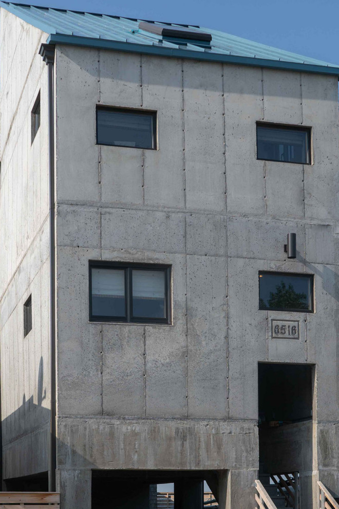 Cette image montre une petite façade de maison grise urbaine en béton à un étage avec un toit en appentis.