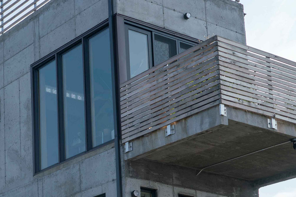 Imagen de fachada de casa gris urbana pequeña de dos plantas con revestimiento de hormigón, tejado plano y tejado de varios materiales