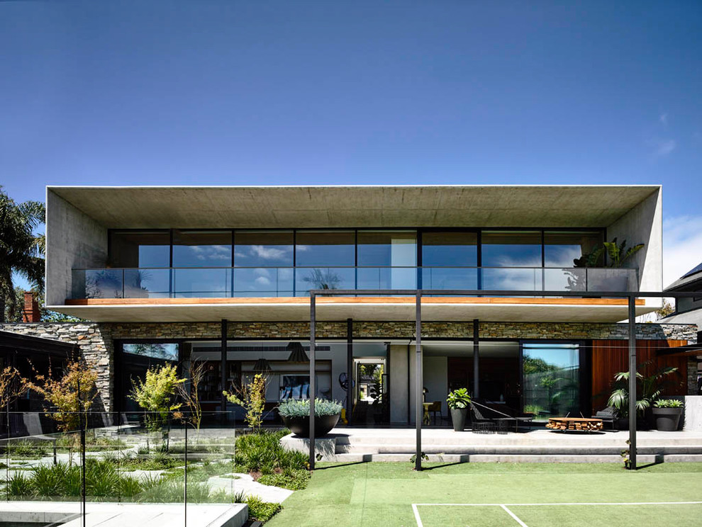 Foto de fachada de casa gris moderna de dos plantas con revestimiento de piedra y tejado plano