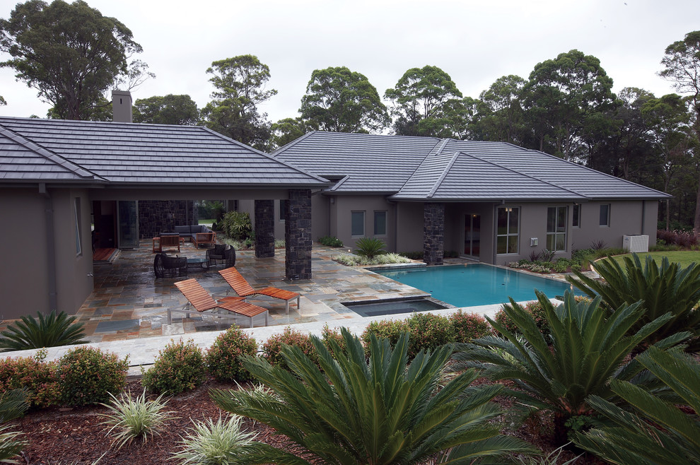 Пример оригинального дизайна: одноэтажный, серый дом среднего размера в классическом стиле с облицовкой из бетона и вальмовой крышей