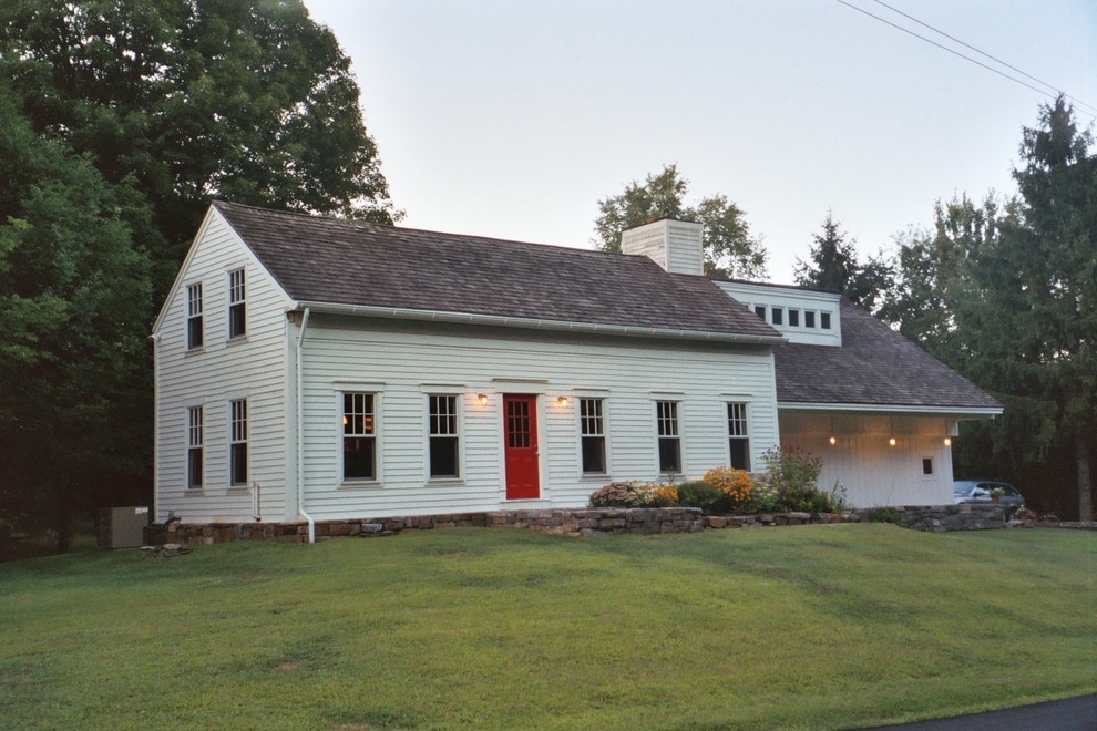 Foto della facciata di una casa bianca country a due piani con rivestimento in legno