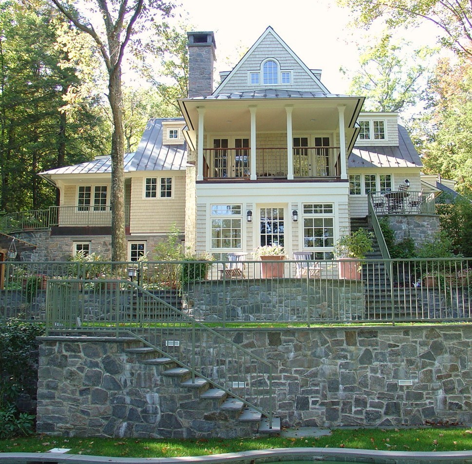Immagine della facciata di una casa grande gialla classica a tre piani con rivestimenti misti e falda a timpano