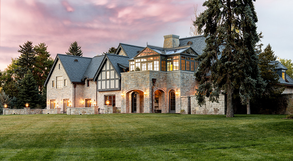 Huge traditional gray two-story stone exterior home idea in Denver with a hip roof