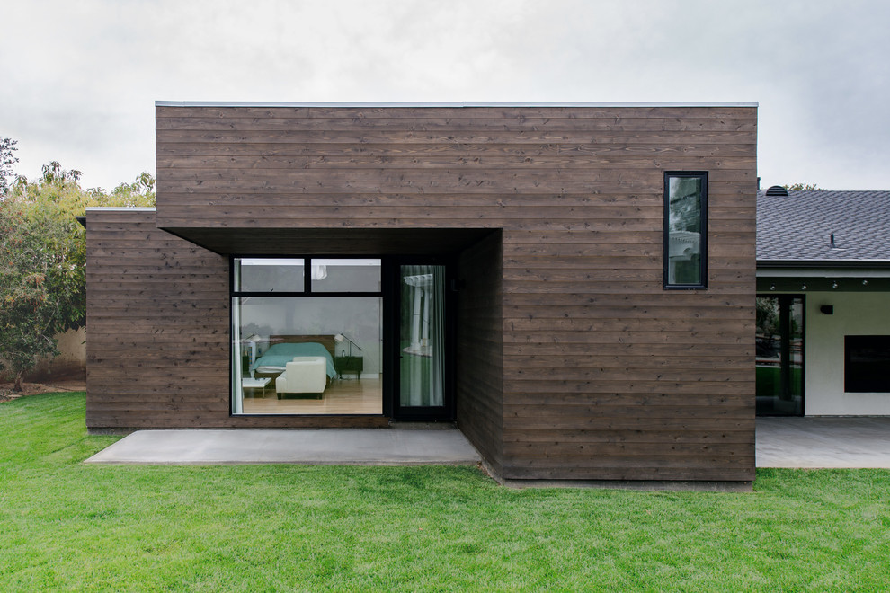 Diseño de fachada marrón moderna grande de una planta con revestimiento de madera y tejado plano