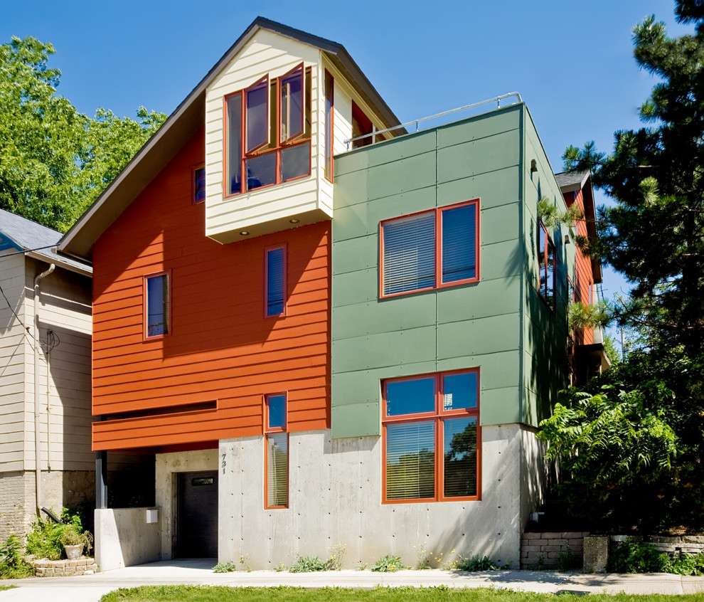 На фото: большой, трехэтажный, оранжевый дом в стиле модернизм с комбинированной облицовкой, двускатной крышей и крышей из гибкой черепицы с