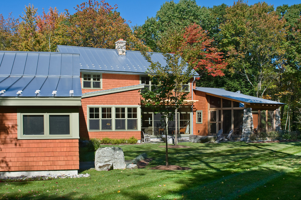 Réalisation d'une grande façade de maison rouge craftsman en bois à un étage avec un toit à croupette et un toit en métal.